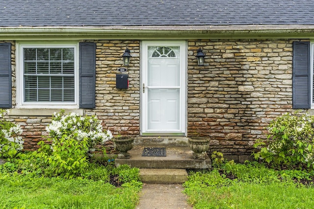 property entrance with roof with shingles and stone siding