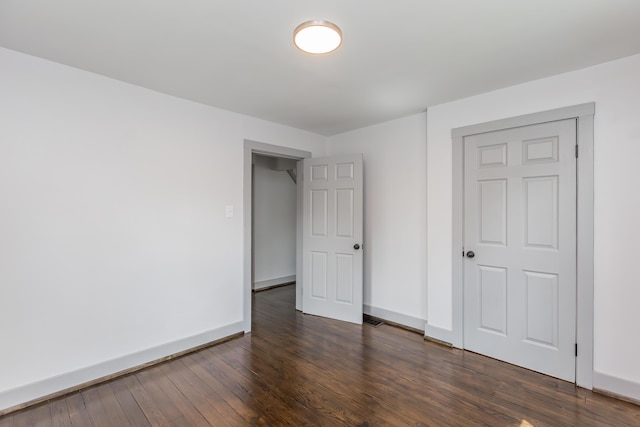 unfurnished bedroom with dark wood-type flooring and baseboards