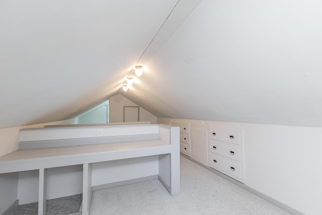 additional living space with vaulted ceiling, light colored carpet, and baseboards