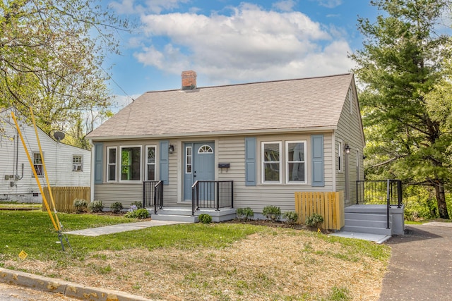 view of front facade featuring a chimney, fence, a shingled roof, and a front yard