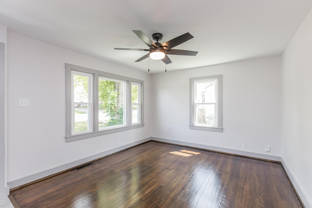 spare room featuring dark wood-style flooring, visible vents, a ceiling fan, and baseboards
