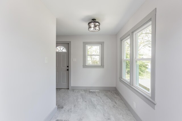 foyer entrance with a healthy amount of sunlight, marble finish floor, and baseboards