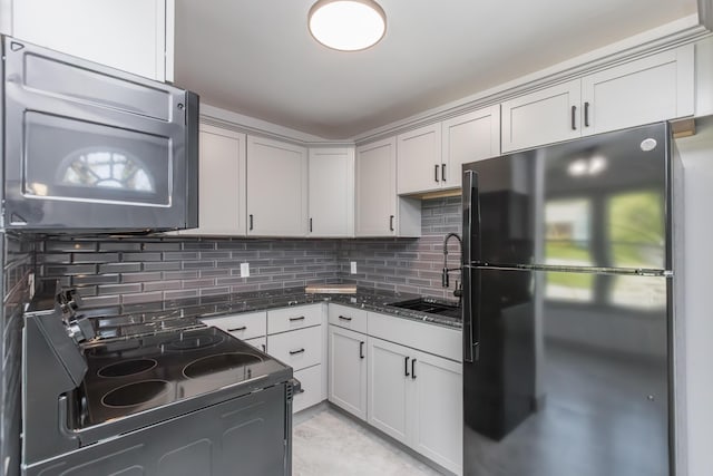 kitchen with a sink, electric range, decorative backsplash, and freestanding refrigerator