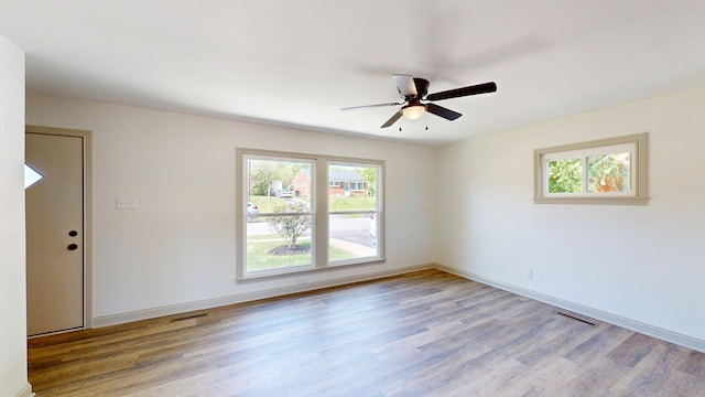 spare room with baseboards, ceiling fan, wood finished floors, and visible vents