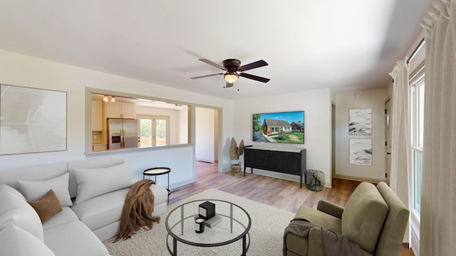 living area featuring ceiling fan, baseboards, and light wood-type flooring
