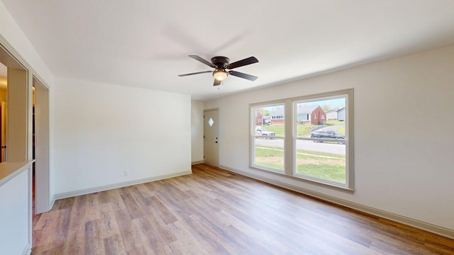 spare room featuring baseboards, light wood finished floors, and ceiling fan