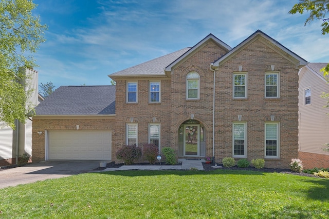 colonial inspired home featuring brick siding, a shingled roof, a garage, a front yard, and concrete driveway