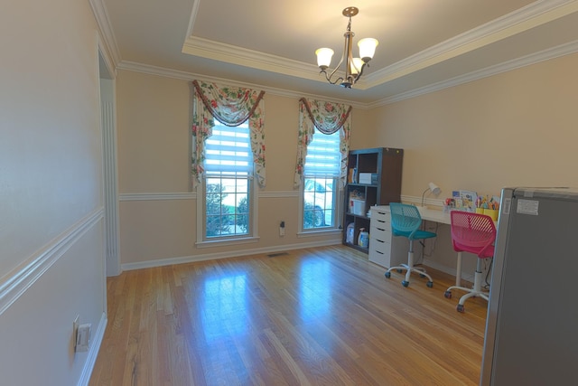 home office featuring light wood-type flooring, ornamental molding, an inviting chandelier, and a raised ceiling