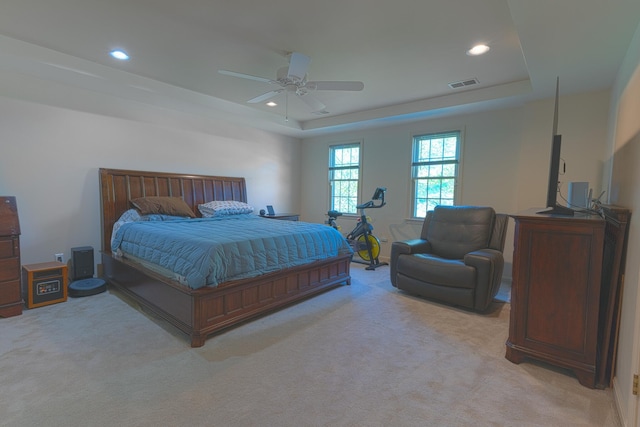 bedroom featuring visible vents, recessed lighting, a tray ceiling, and light carpet