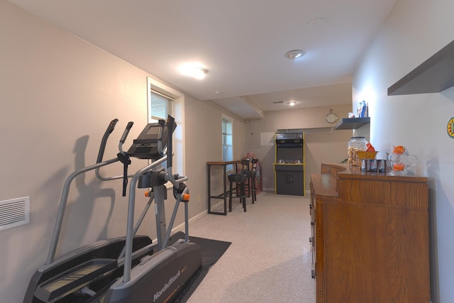 exercise area featuring visible vents, light carpet, and baseboards