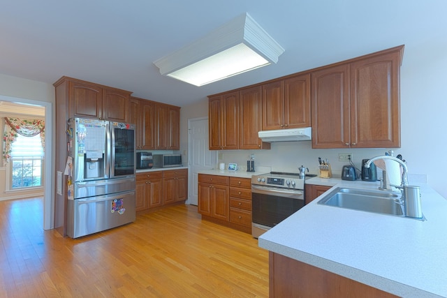 kitchen with light wood-style flooring, a sink, appliances with stainless steel finishes, and under cabinet range hood