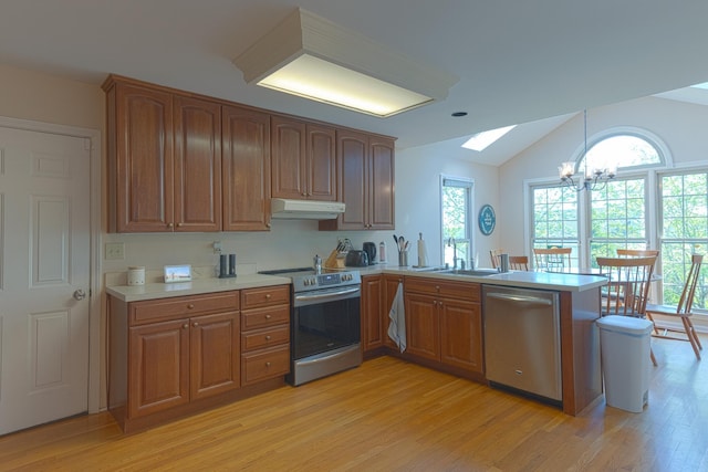 kitchen featuring an inviting chandelier, under cabinet range hood, appliances with stainless steel finishes, light wood finished floors, and a peninsula