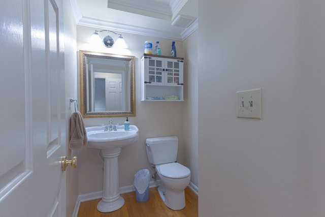 half bath featuring ornamental molding, toilet, wood finished floors, and baseboards
