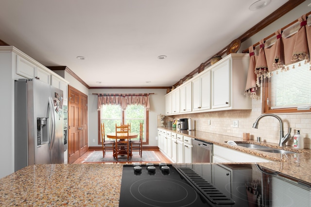 kitchen featuring crown molding, white cabinets, light stone countertops, a sink, and stainless steel appliances