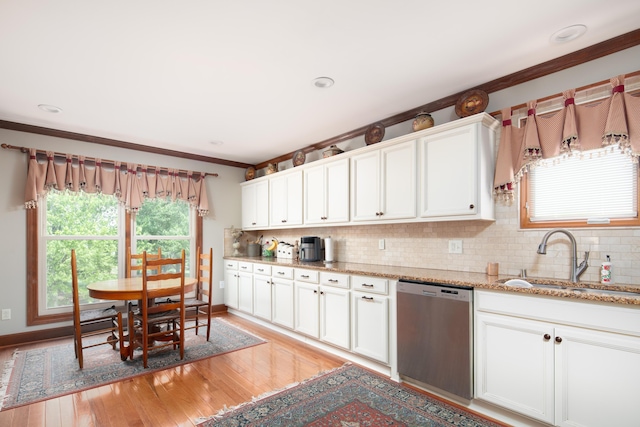 kitchen with stainless steel dishwasher, decorative backsplash, crown molding, light wood-type flooring, and a sink