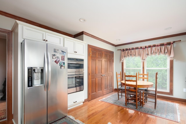 kitchen with stainless steel appliances, baseboards, white cabinetry, and light wood-style flooring