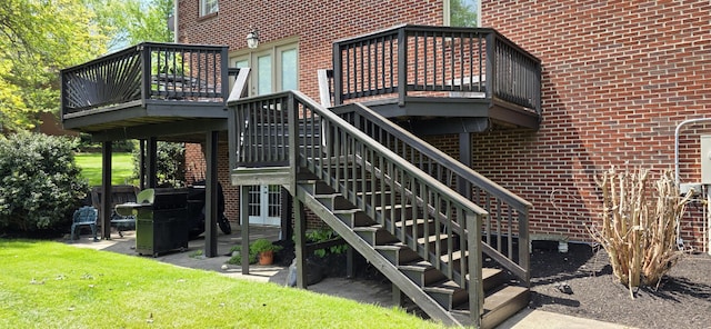 exterior space with a wooden deck, a patio area, stairway, and brick siding