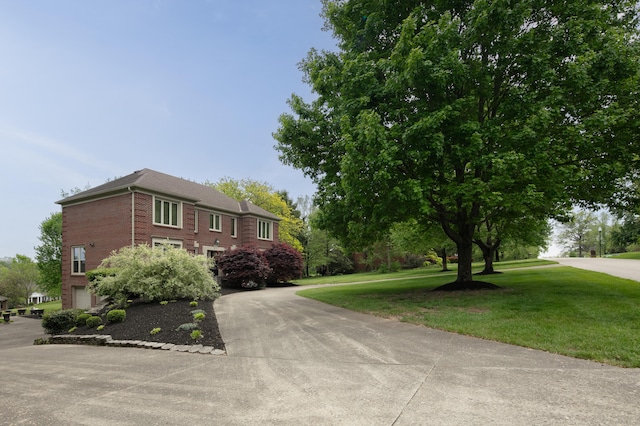 view of front facade featuring an attached garage, concrete driveway, a front lawn, and brick siding