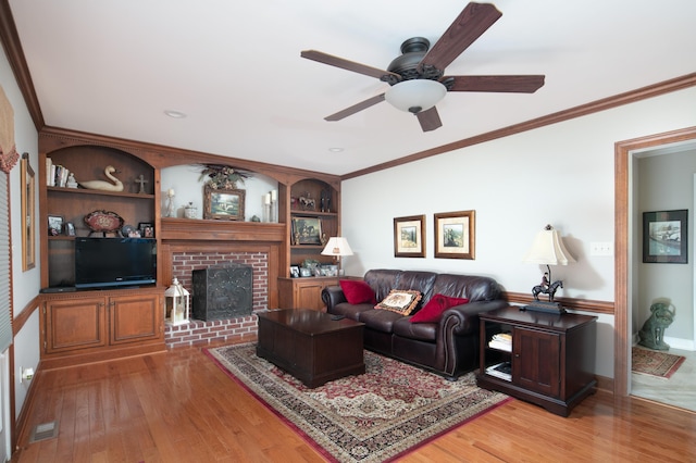 living room with ceiling fan, visible vents, ornamental molding, and light wood-type flooring
