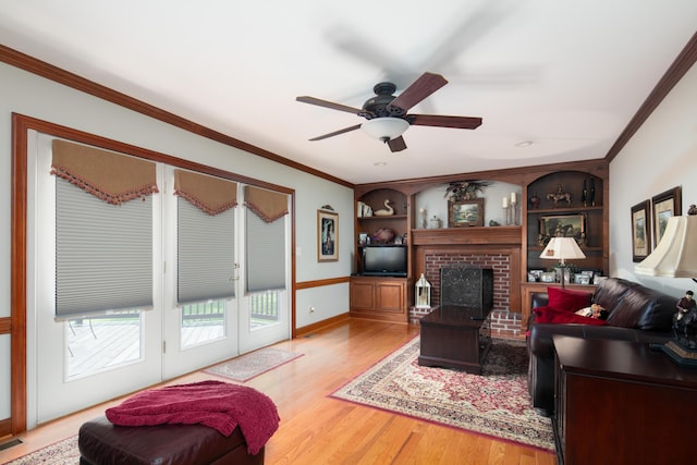 living area with a ceiling fan, ornamental molding, wood finished floors, and a fireplace