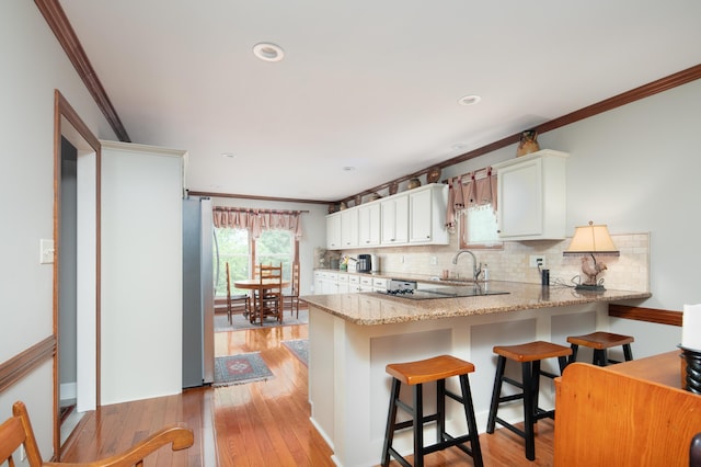 kitchen featuring ornamental molding, a peninsula, backsplash, and freestanding refrigerator