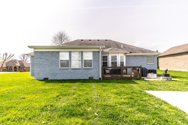 rear view of property featuring a deck, a yard, and brick siding