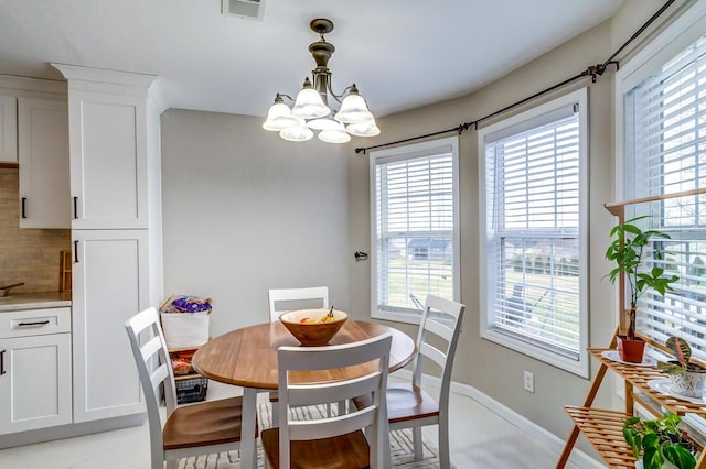 dining space with visible vents, an inviting chandelier, baseboards, and plenty of natural light