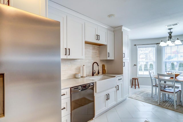 kitchen featuring stainless steel fridge, black dishwasher, light countertops, backsplash, and visible vents
