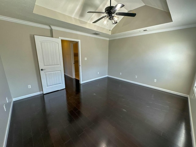 spare room featuring a raised ceiling, visible vents, baseboards, dark wood-style flooring, and a ceiling fan