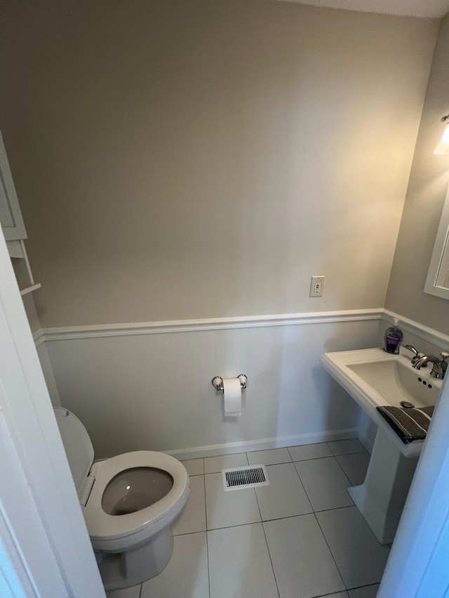 bathroom featuring visible vents, wainscoting, toilet, tile patterned floors, and a sink