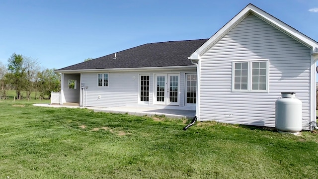 rear view of house with a lawn, french doors, and a patio area