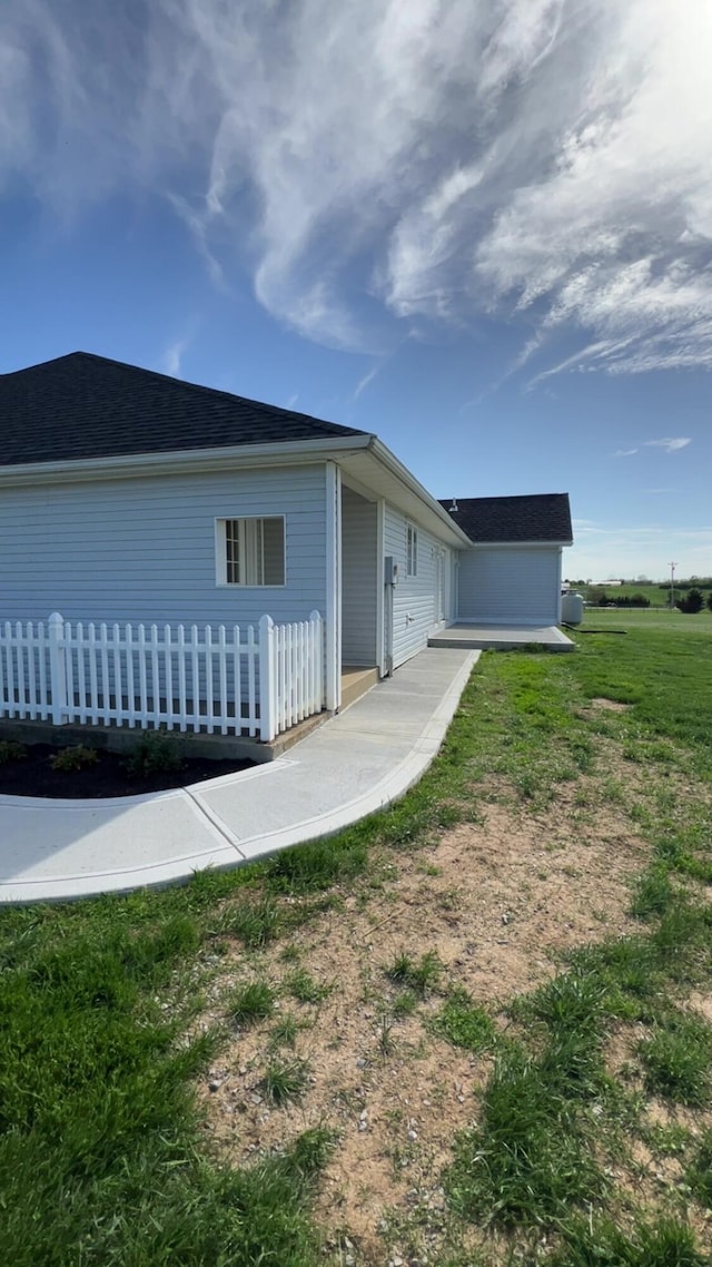 view of home's exterior with a shingled roof and fence
