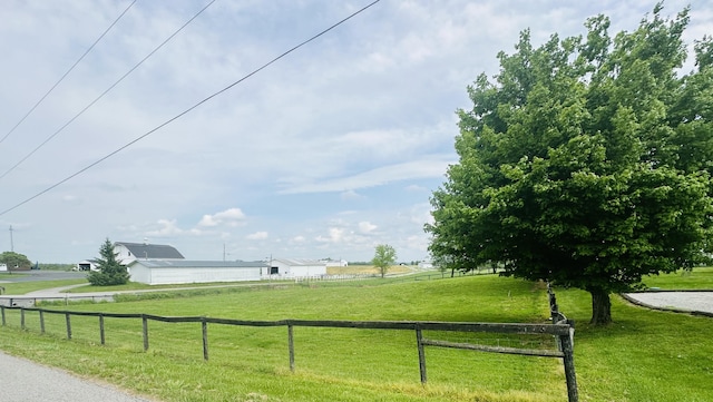 surrounding community featuring fence, a yard, and a rural view