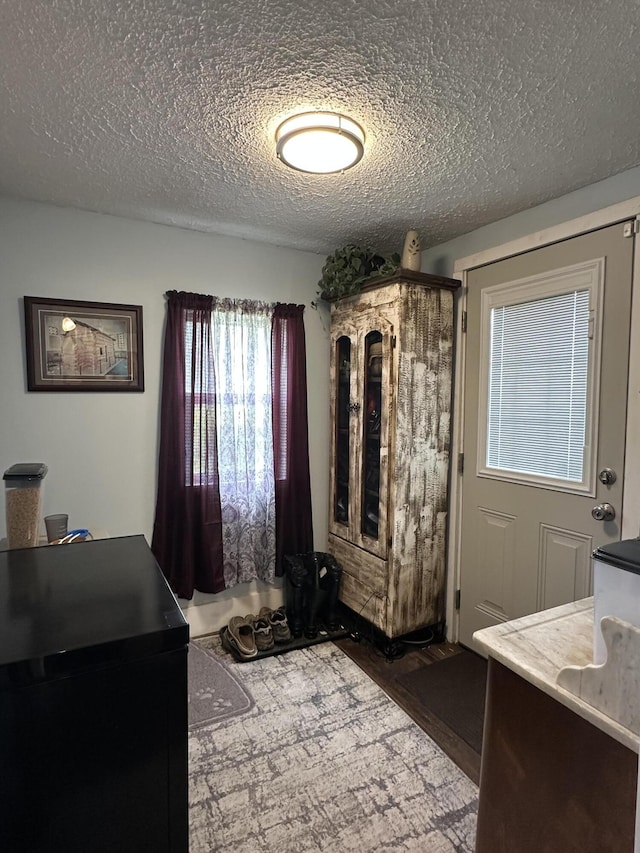 interior space with a textured ceiling and wood finished floors