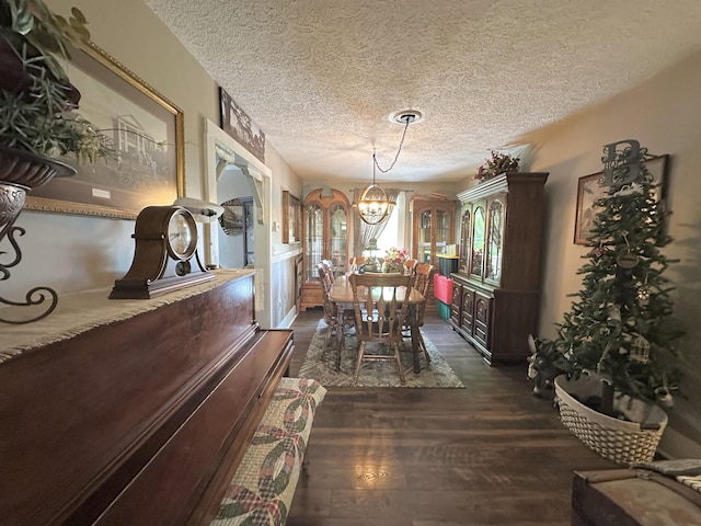 dining space featuring an inviting chandelier, dark wood-style floors, and a textured ceiling