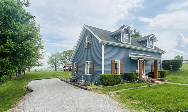 view of home's exterior featuring a lawn, roof with shingles, a chimney, and gravel driveway