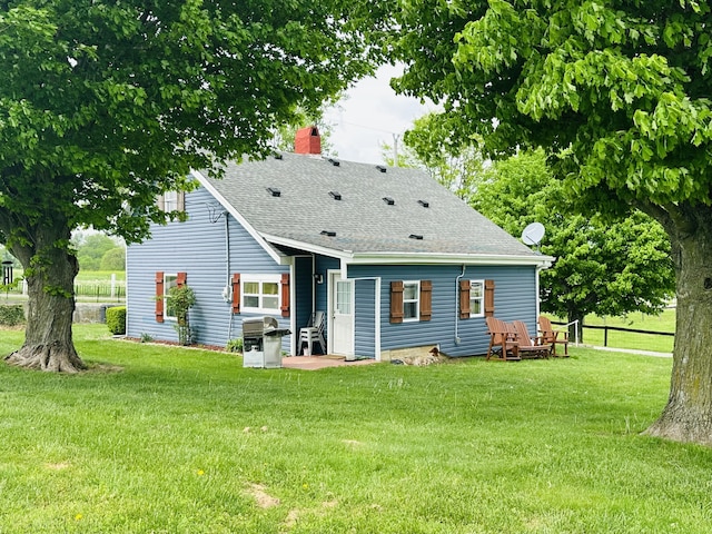 back of property featuring a lawn, a shingled roof, fence, and a chimney