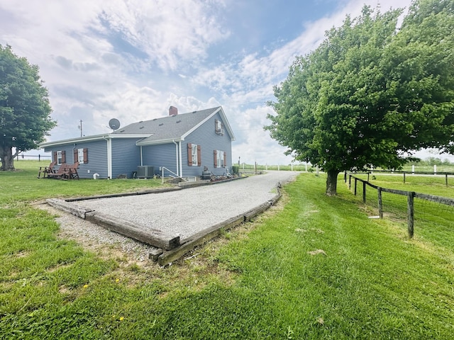 exterior space featuring a lawn, central AC, fence, and driveway