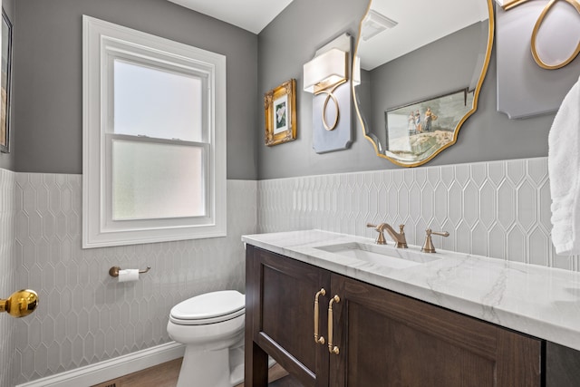 bathroom with toilet, visible vents, wainscoting, and vanity