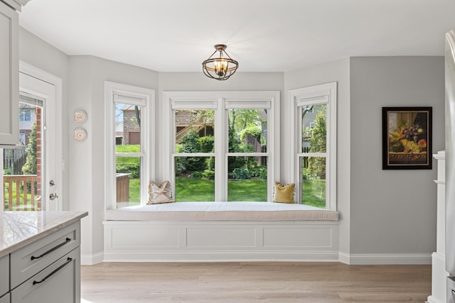 doorway to outside with an inviting chandelier, baseboards, and light wood-style flooring