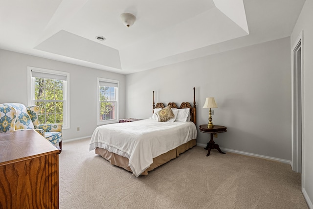 bedroom featuring light colored carpet, baseboards, a tray ceiling, and visible vents