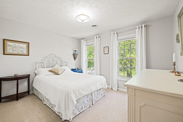 bedroom with light colored carpet, a textured ceiling, and baseboards