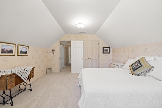 carpeted bedroom with visible vents, a closet, wallpapered walls, and lofted ceiling