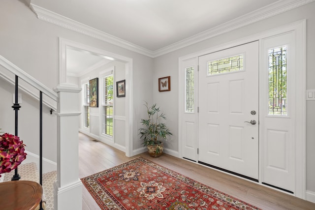foyer with ornamental molding and light wood finished floors