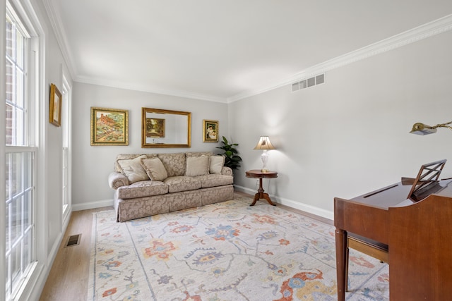 living area with crown molding, wood finished floors, and visible vents