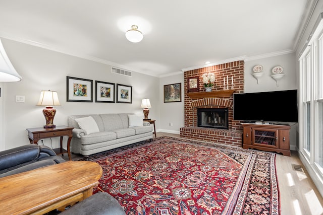 living area featuring crown molding, baseboards, a brick fireplace, and visible vents