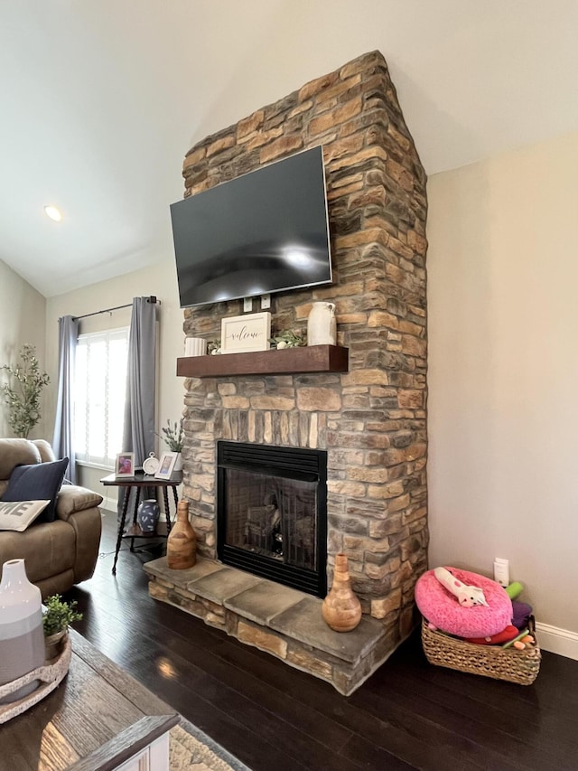 living area featuring a stone fireplace, baseboards, vaulted ceiling, and hardwood / wood-style floors