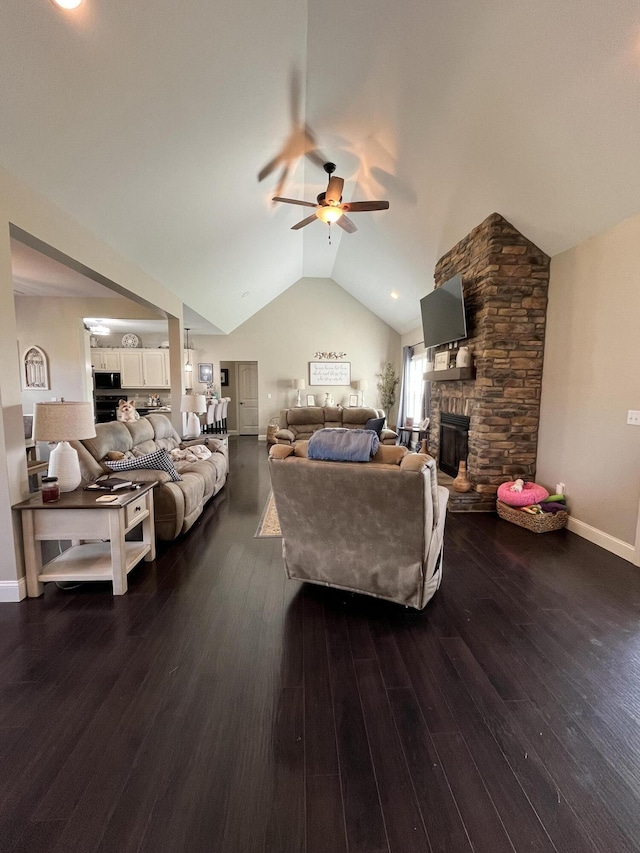 living room featuring lofted ceiling, wood finished floors, a stone fireplace, baseboards, and a ceiling fan