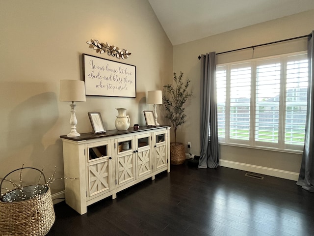 interior space featuring baseboards, visible vents, lofted ceiling, and dark wood-type flooring