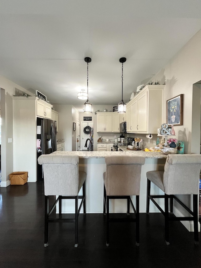 kitchen featuring a peninsula, a kitchen bar, light countertops, a sink, and appliances with stainless steel finishes